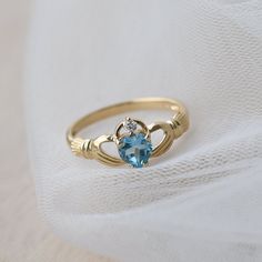 Delicate and symbolic Claddagh ring is made out of 14k solid gold and set with blue heart topaz and diamond It would make a perfect choice for the engagement or as a push gift. Ring can be made in white, rose or yellow 14k gold. Highly polished. If you want to customise this product or set it with another stones - please write to us. ❤ Hand Made with love in our studio in Prague ❤ Stone details Topaz Shape: Heart Dimensions: 5.7 mm Color: Blue Origin: Natural Diamond Amount: 1 Shape: Round Color Heart Cut Topaz Ring For Promise, Heart Cut Topaz Gemstone Ring For Promise, Heart Cut Topaz Promise Ring, Promise Jewelry With Topaz Birthstone, Topaz Birthstone Promise Ring In Fine Jewelry Style, Topaz Birthstone Promise Ring Fine Jewelry, Fine Jewelry Topaz Birthstone Promise Ring, Heart Cut Topaz Birthstone Ring For Anniversary, Promise Yellow Gold Topaz Ring