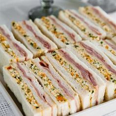 several sandwiches are arranged on a white platter and ready to be served at a party