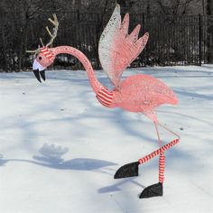 a pink flamingo standing on top of snow covered ground