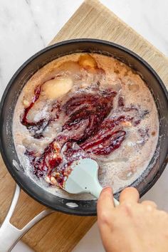 someone mixing batter in a pan with bananas and cherries