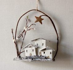 a white house ornament hanging on a wall next to a tree branch and star