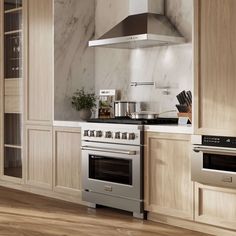 a kitchen with marble counter tops and stainless steel ovens, stove hood over the range