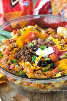 a glass bowl filled with mexican food and tortilla chips