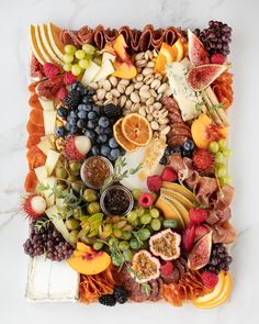 an assortment of fruits and vegetables arranged in a square shape on a white marble surface