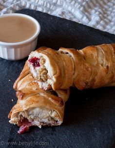 a croissant is cut in half on a black plate next to a cup of coffee