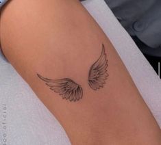 a woman's arm with an angel wing tattoo on it