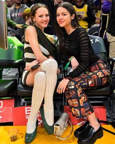 two young women sitting next to each other at a basketball game