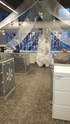 an office decorated for christmas with balloons and snowflakes hanging from the ceiling over cubicles