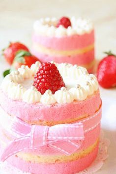 there are two cakes with strawberries on the top one is pink and the other is white