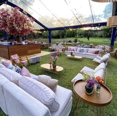 an outdoor seating area with couches, tables and flowers in vases on the grass