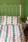 a bed with a pink and green bedspread on it