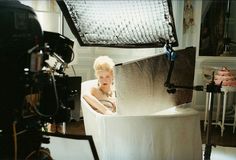 a woman is sitting in a bathtub surrounded by lights and camera's equipment