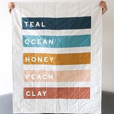 a person holding up a poster with words on it that say teal, ocean, honey, peach and clay