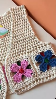 two crocheted aprons with flowers on them sitting on a counter top next to each other