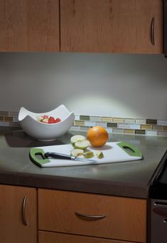 a cutting board with sliced fruit on top of it next to a knife and bowl