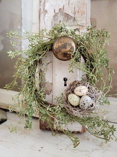 an old door is decorated with a wreath and eggs in the nest on it's side