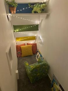 a room with some plants and lights on the wall next to a green chair in front of a couch