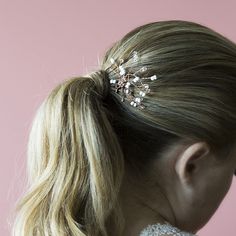 a woman wearing a hair comb with pearls on it's head and long blonde hair