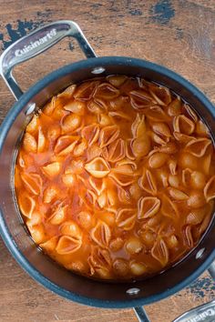 a pot filled with pasta and sauce on top of a wooden table