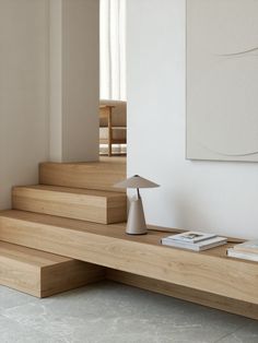 a wooden table with a lamp on top of it next to some books and magazines