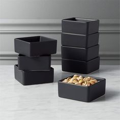 four square containers with nuts in them on a table top next to a wall and floor