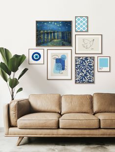 a couch sitting in front of a wall with pictures on the wall and a potted plant next to it