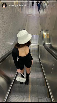 a woman in short shorts and a hat riding an escalator with her back to the camera