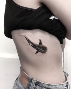 a black and white photo of a woman's stomach with a shark tattoo on it