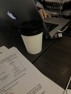 a person sitting at a table with a laptop and coffee cup in front of them