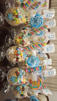 a table topped with lots of candy and lollipops on top of plastic cups