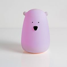 a pink bear shaped object sitting on top of a white table next to a wall