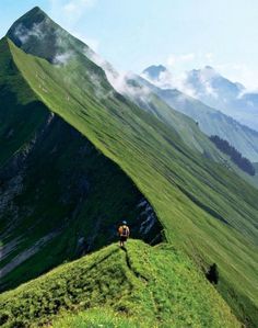 a man hiking up the side of a green mountain