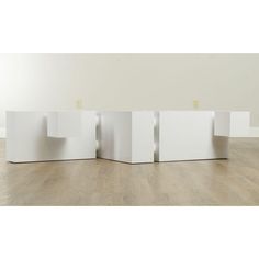 three white cubes sitting on top of a wooden floor next to each other in front of a wall