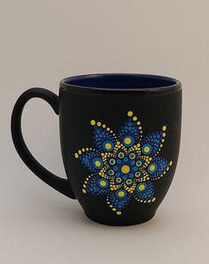 a black coffee cup with blue and yellow designs on it