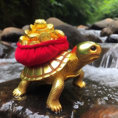 a gold turtle with a red bag on its back sitting on top of a rock