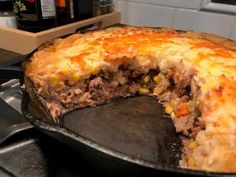 a meat and vegetable pie is shown in a skillet on the stove with a slice missing from it