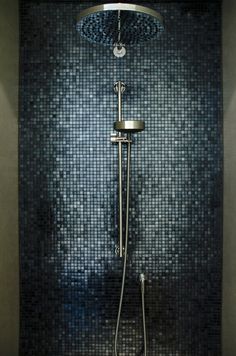 a shower head and hand held shower faucet in a modern bathroom with black mosaic tile