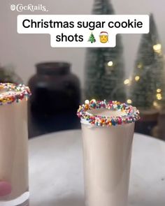 two glasses filled with white chocolate and sprinkles on top of a table