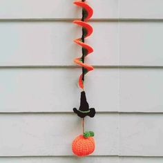 an orange and black crocheted halloween decoration hanging on the side of a house