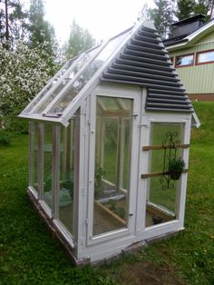 a small white greenhouse sitting on top of a lush green field