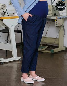 a pregnant woman standing in front of a sewing machine with her hands on her hips