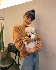 a woman standing next to a chair holding two stuffed animals