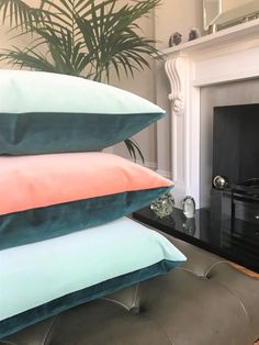 four pillows stacked on top of each other in front of a fireplace with a plant