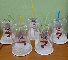 four snowmen with hats and scarfs on their heads are in plastic bags, sitting on a table