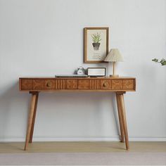 a wooden table with two drawers and a lamp on it next to a white wall