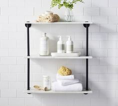 three shelves with towels, soaps and other items on them in a white tiled bathroom