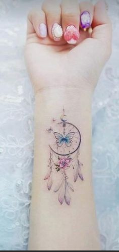 a woman's wrist tattoo with a butterfly and dream catcher on the left side