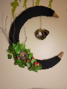 a wreath made to look like the letter o with leaves and berries on it hanging from a wall