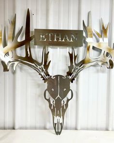 a metal deer head mounted to the side of a wall with an ethan sign above it