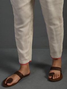 a person with sandals on their feet standing in front of a gray background